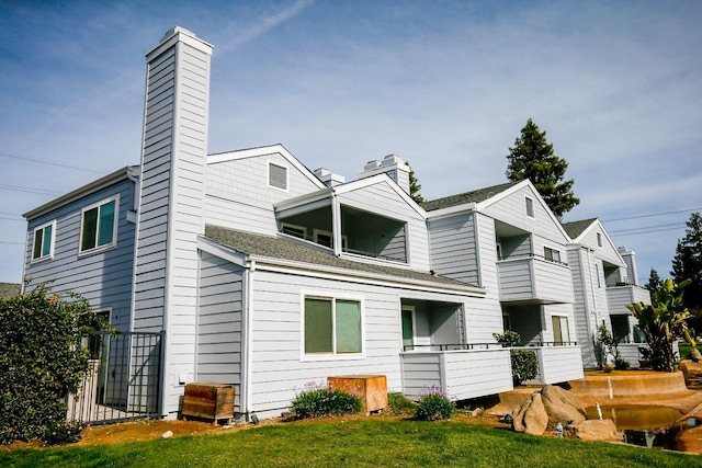 rear view of house featuring a chimney and a lawn