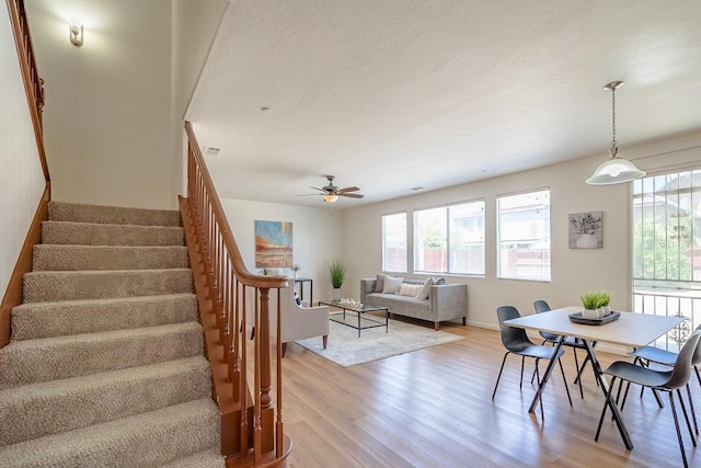 stairway featuring a textured ceiling, a ceiling fan, a wealth of natural light, and wood finished floors