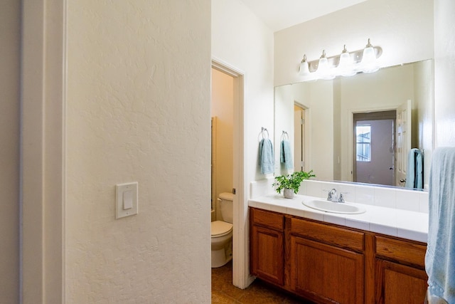 bathroom featuring a textured wall, vanity, toilet, and tile patterned floors