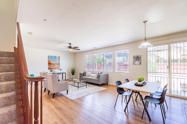 dining space featuring a textured ceiling, a ceiling fan, visible vents, stairway, and light wood finished floors