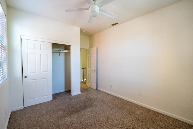 unfurnished bedroom featuring carpet flooring, a ceiling fan, visible vents, baseboards, and a closet