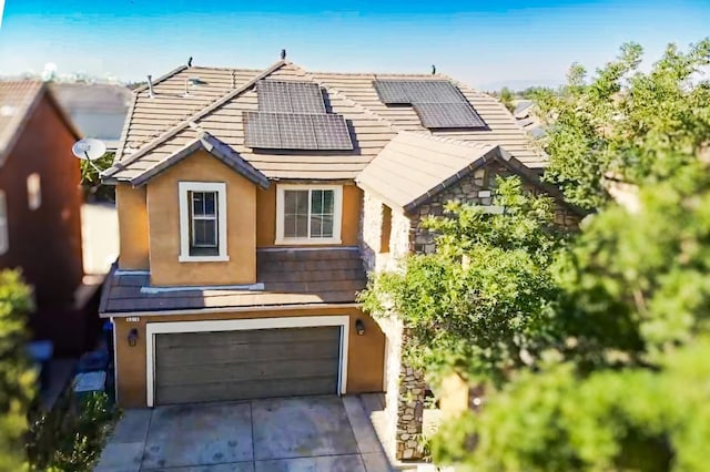 view of front of house with roof mounted solar panels, concrete driveway, and stucco siding