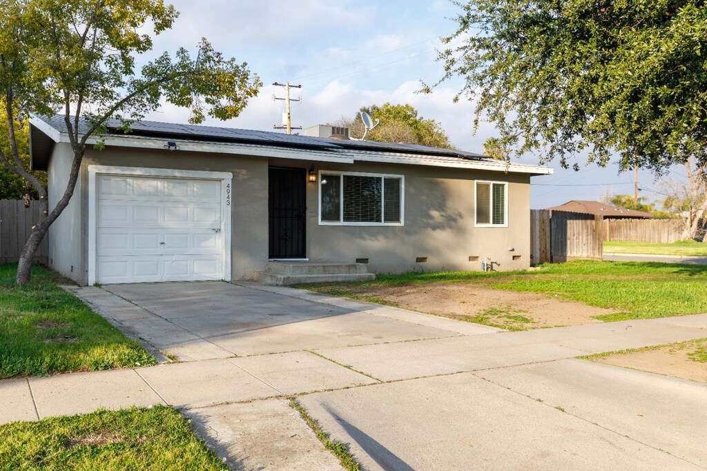 4943 E Nevada Ave, Fresno, CA 93727 - single story home with solar panels, an attached garage, concrete driveway, and crawl space