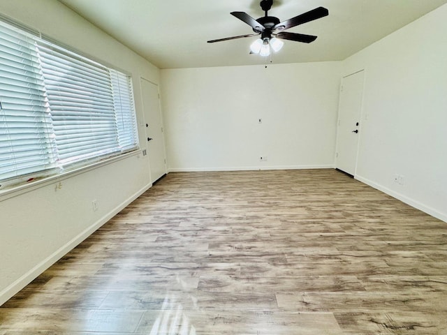 unfurnished room featuring ceiling fan, light wood-style flooring, and baseboards