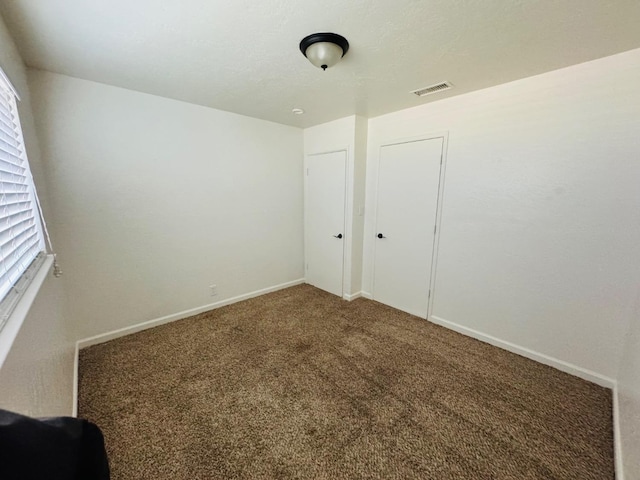 unfurnished bedroom with carpet floors, baseboards, visible vents, and a closet