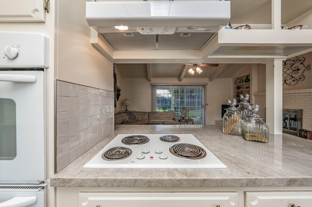 kitchen featuring open floor plan, light countertops, white appliances, and white cabinetry