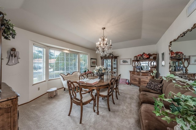 dining room with a tray ceiling, a notable chandelier, visible vents, light carpet, and baseboards