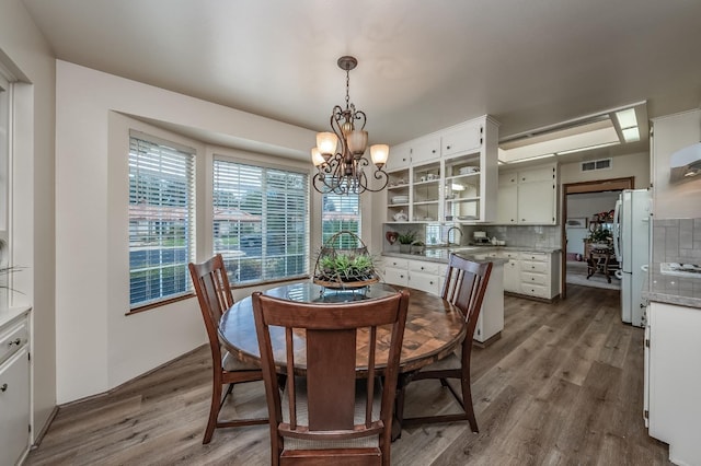 dining space with visible vents, an inviting chandelier, and wood finished floors