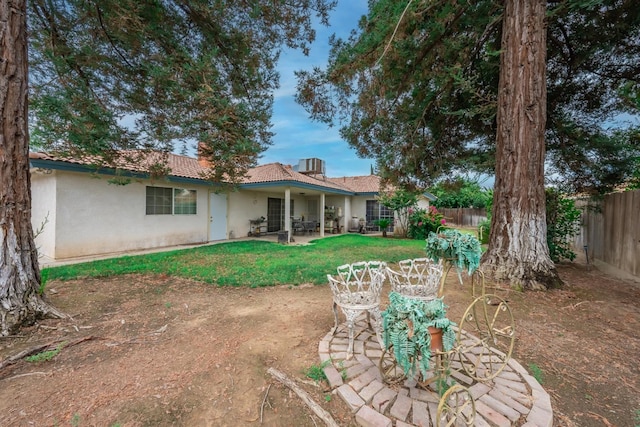 rear view of property with stucco siding, fence, a lawn, and a patio