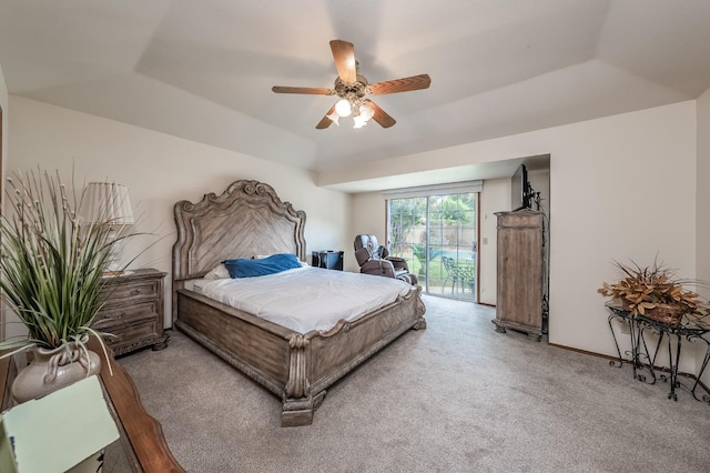 bedroom featuring a ceiling fan, baseboards, access to outside, a tray ceiling, and carpet