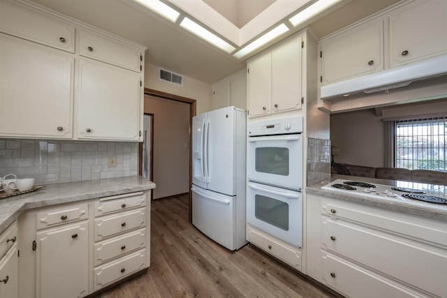 kitchen with white appliances, visible vents, white cabinets, light countertops, and light wood finished floors