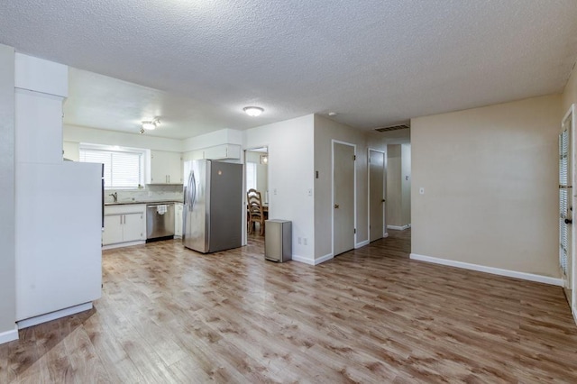 kitchen featuring baseboards, white cabinets, visible vents, stainless steel appliances, and light wood-style floors