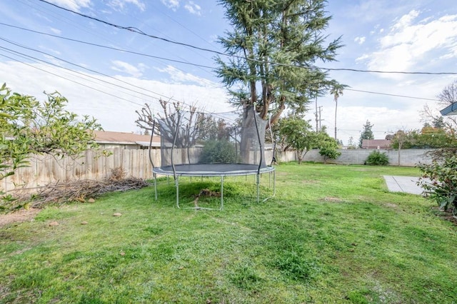 view of yard featuring a trampoline and a fenced backyard