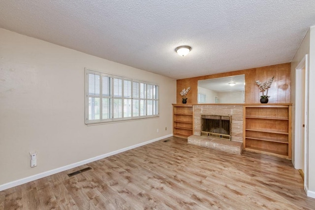 unfurnished living room with light wood finished floors, baseboards, a fireplace, and visible vents