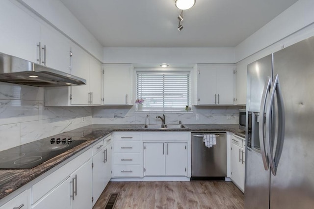 kitchen with white cabinets, stainless steel appliances, light wood-type flooring, under cabinet range hood, and a sink