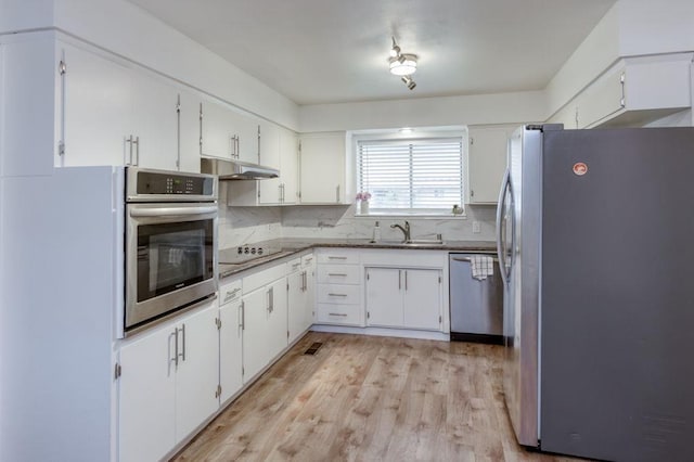 kitchen featuring under cabinet range hood, white cabinetry, appliances with stainless steel finishes, and a sink