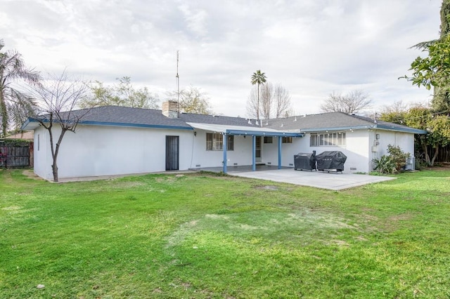 rear view of property featuring a patio, fence, a yard, stucco siding, and a chimney