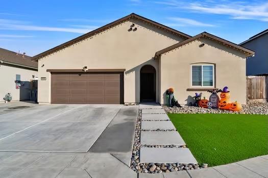 view of front of house featuring a garage, a front yard, driveway, and stucco siding