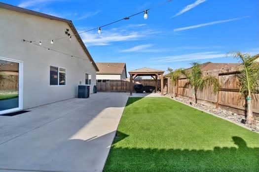 view of yard featuring a gazebo, central AC unit, a patio area, and a fenced backyard