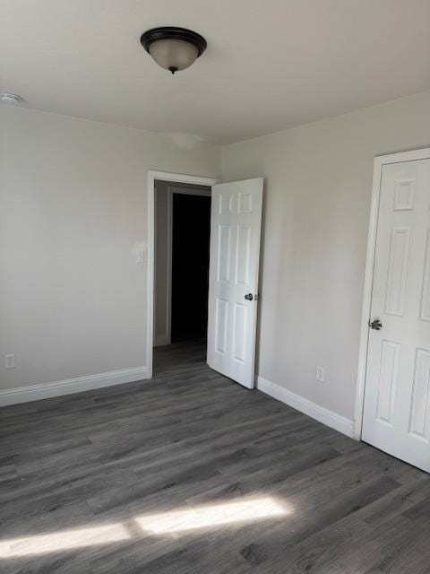 spare room featuring dark wood-style flooring and baseboards