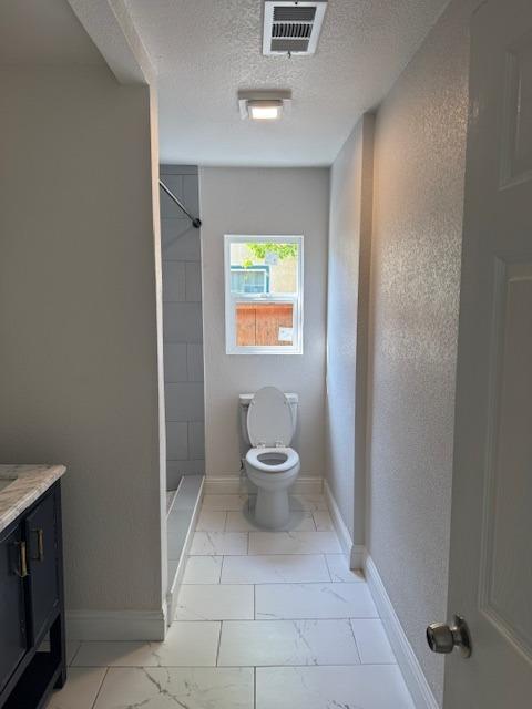 bathroom with toilet, visible vents, baseboards, marble finish floor, and a stall shower