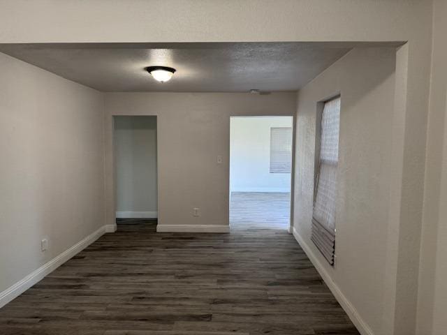 unfurnished room with dark wood-style floors, baseboards, and a textured ceiling