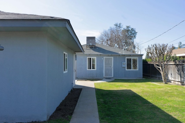 exterior space featuring central AC unit, a lawn, and fence