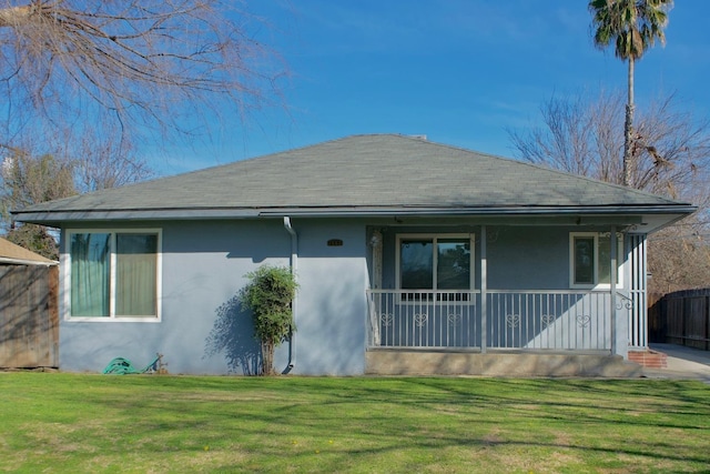 view of front of home with roof with shingles, a front yard, and stucco siding