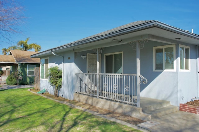 view of front of home featuring a porch, a front lawn, and stucco siding