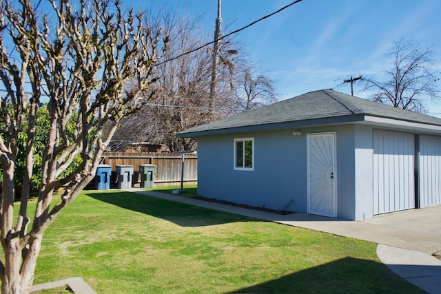 exterior space with an outbuilding, a shingled roof, fence, a yard, and stucco siding