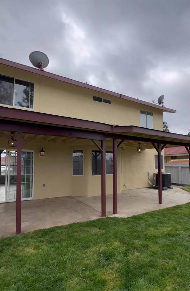 back of house with a patio, central air condition unit, fence, a yard, and stucco siding