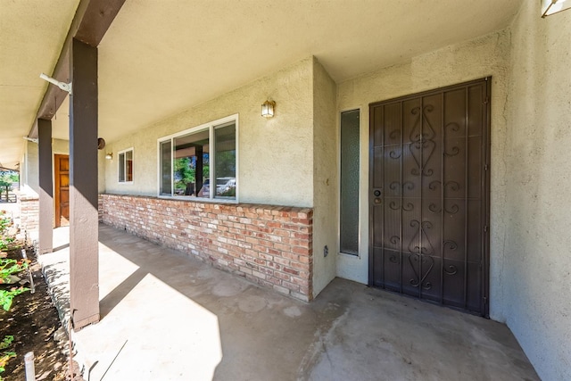 doorway to property featuring brick siding and stucco siding