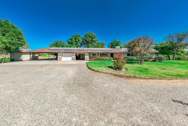 single story home with an attached garage, an attached carport, gravel driveway, and a front yard