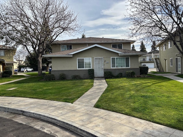 view of front of house featuring brick siding, a front lawn, and stairs