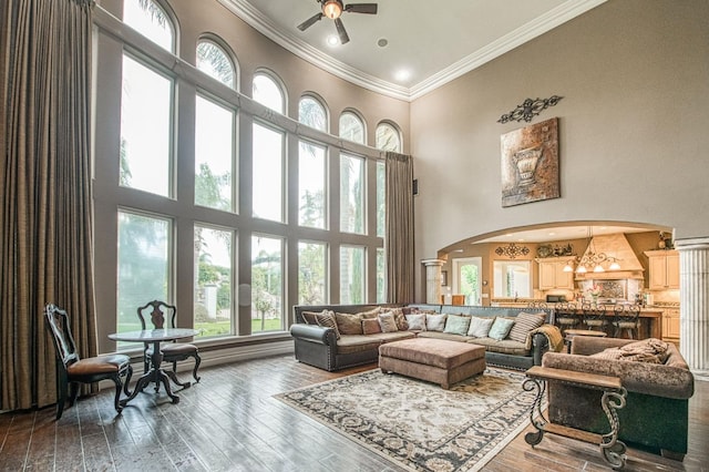 living area featuring arched walkways, crown molding, a high ceiling, ceiling fan, and wood finished floors