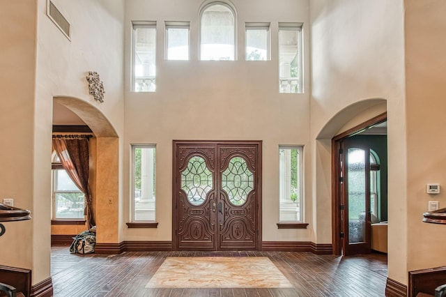 foyer with arched walkways, wood finished floors, visible vents, and baseboards