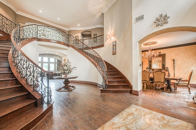 foyer featuring visible vents, crown molding, arched walkways, and wood finished floors