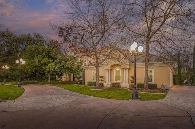 view of front of house with driveway, stucco siding, and a yard