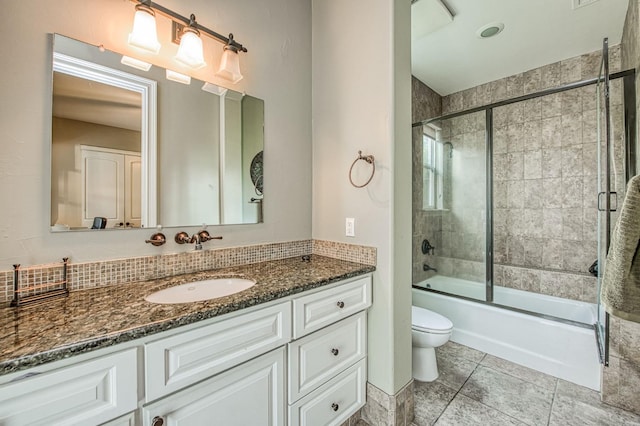 full bathroom featuring tile patterned floors, vanity, toilet, and bath / shower combo with glass door