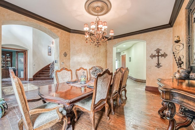 dining area featuring arched walkways, crown molding, a notable chandelier, wood-type flooring, and baseboards