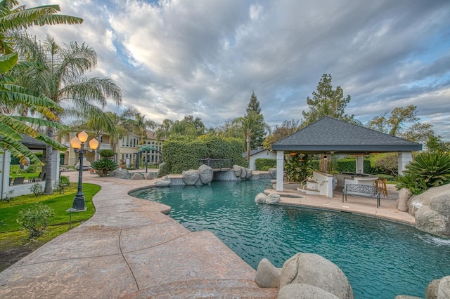 outdoor pool with area for grilling, a patio, and a gazebo