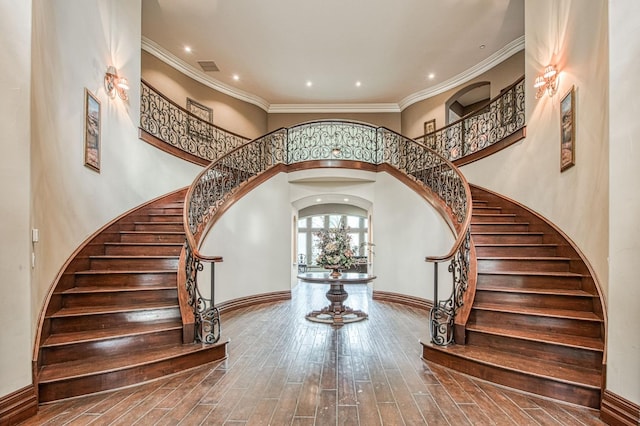 stairway with arched walkways, visible vents, ornamental molding, wood finished floors, and baseboards