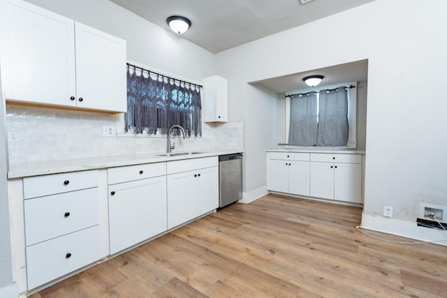 kitchen with light countertops, backsplash, white cabinetry, a sink, and dishwasher