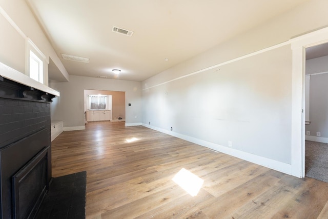 unfurnished living room featuring light wood finished floors, visible vents, and baseboards