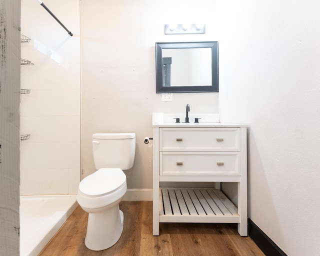 bathroom with baseboards, toilet, wood finished floors, walk in shower, and vanity