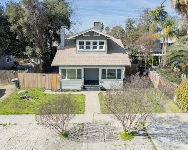 bungalow-style house with roof with shingles, a fenced front yard, and a chimney