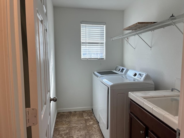 clothes washing area with cabinet space, baseboards, and washing machine and clothes dryer