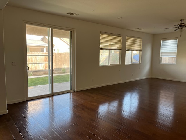 empty room with baseboards, visible vents, and dark wood-style flooring