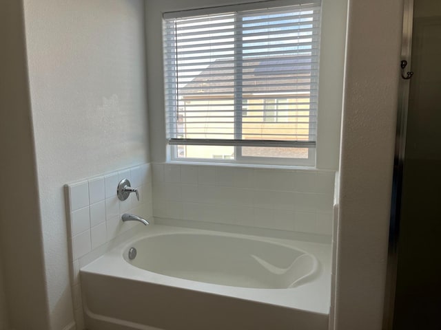 bathroom featuring a garden tub and a textured wall