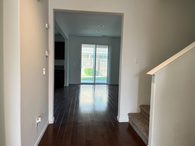 corridor with baseboards, stairway, and dark wood finished floors